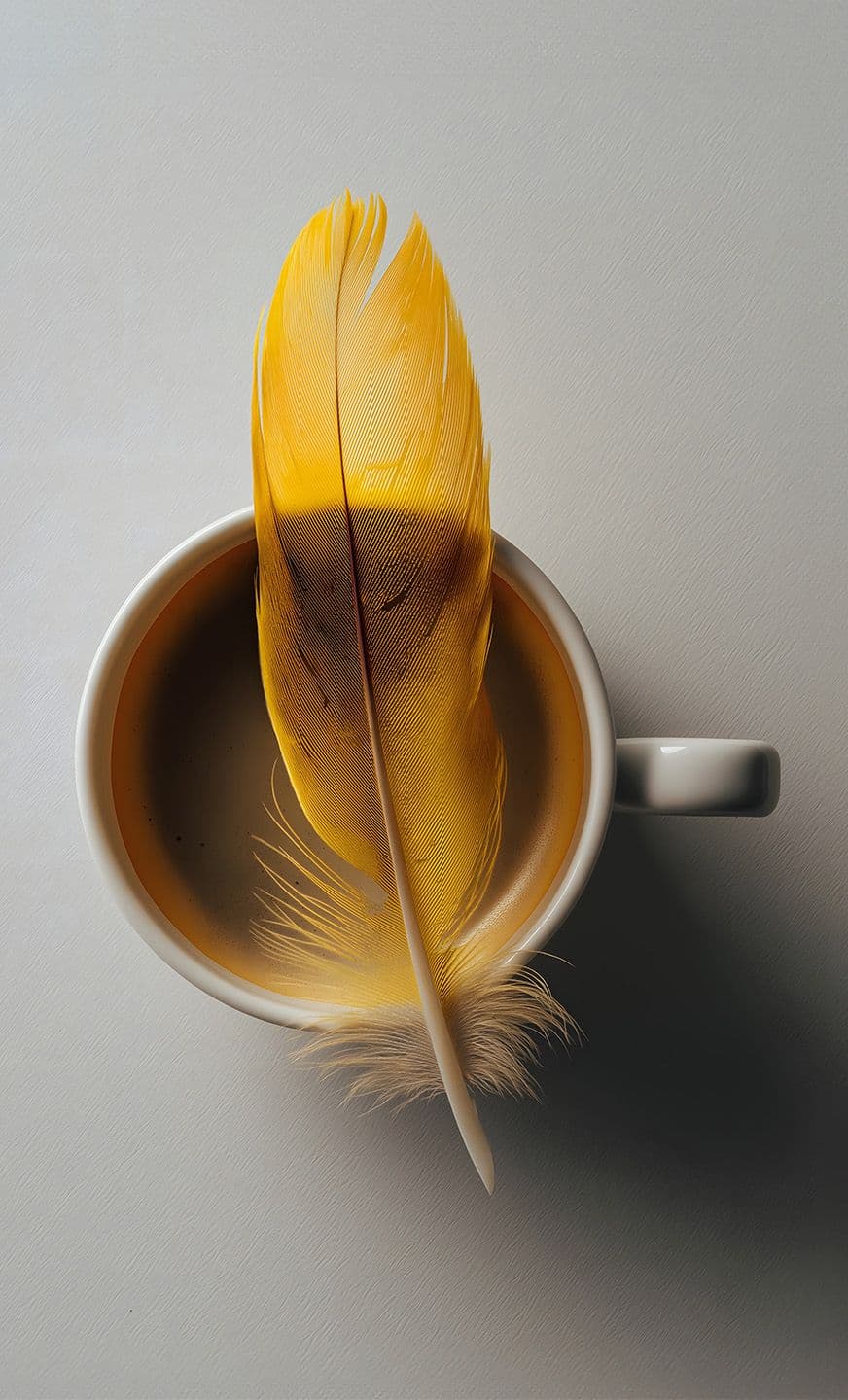 A coffee cup with a yellow feather resting on the brim